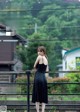 A woman in a black dress standing on a bridge.