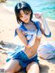 A woman in a blue and white outfit sitting on a beach.