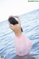 A woman in a pink dress standing in the water.