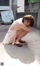 A woman in a white dress crouching down on the ground.