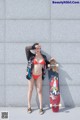 A woman in a red bikini holding a skateboard.