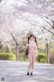 A woman in a pink bikini standing in front of a tree.