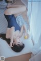 A woman laying on a bed holding an orange.