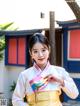 A woman in a yellow and white hanbok poses for a picture.