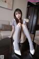 A woman sitting on top of a table wearing white stockings.