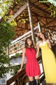 A couple of women standing next to each other on a wooden bridge.