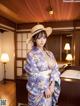 A woman in a kimono and a straw hat posing for a picture.