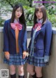 Two young women in school uniforms standing next to each other.