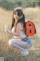 A young woman sitting in a field holding a cell phone.