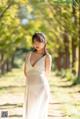 A woman in a white dress standing in a park.