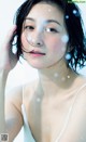 A woman in a white tank top is covered in water droplets.