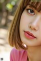 A close up of a woman's face with a pink shirt.