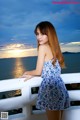 A woman in a blue and white dress leaning on a railing.