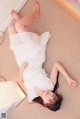 A woman laying on the floor in a white dress.