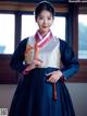 A woman in a blue and white hanbok is posing for a picture.