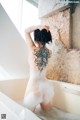 A naked woman with a tattoo on her back in a bathtub.