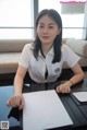 A woman sitting at a table holding a piece of paper.