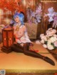 A woman with blue hair sitting on the floor next to a lamp.