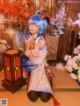 A woman with blue hair sitting on the floor next to a lamp.