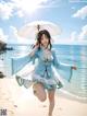 A woman in a blue and white dress holding an umbrella on the beach.