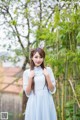 A woman in a blue dress standing in front of a bamboo tree.