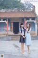 Two young women standing next to each other in front of a building.