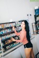 A woman standing in front of a display case filled with cosmetics.